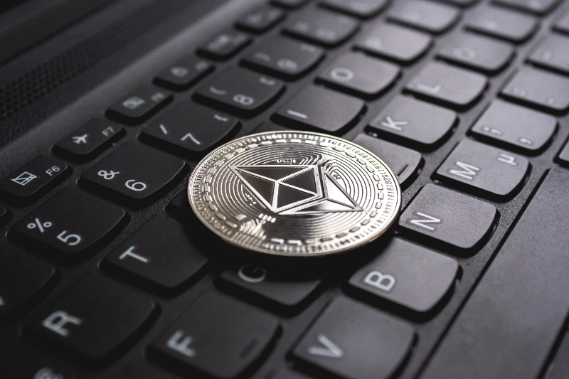 Una moneda metálica plateada de Ethereum sobre las teclas de un ordenador portátil negro.
