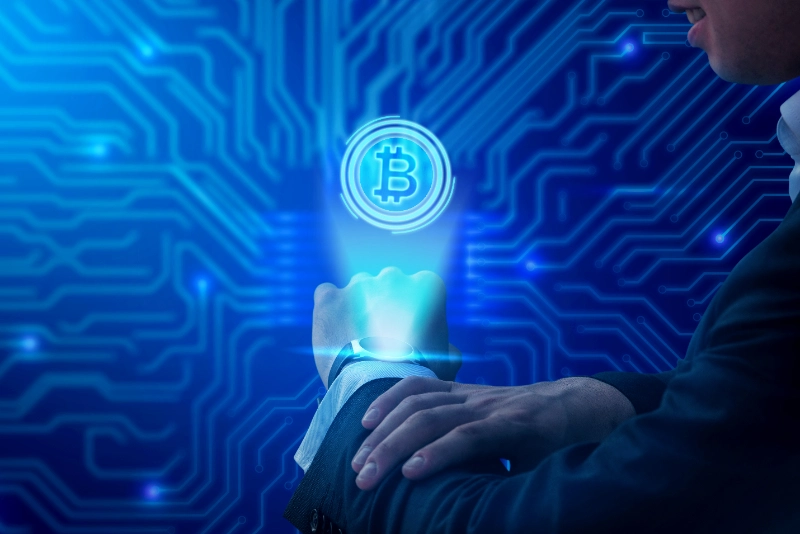 Ejecutivo proyectando el holograma azul del símbolo de bitcoin desde su reloj inteligente sobre un fondo de circuitos digitales.
