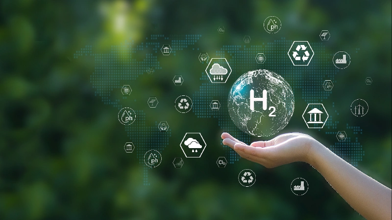 Mano sosteniendo un planeta holográfico con la fórmula H2 rodeado de iconos de energía verde y sostenibilidad sobre un fondo verde.